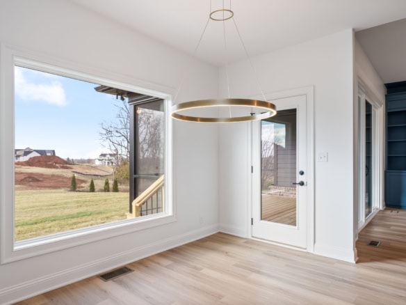 Interior view of dining room with large window and modern lighting fixture.