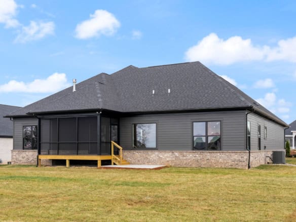 Modern suburban home with screened porch, black siding, and brick foundation.
