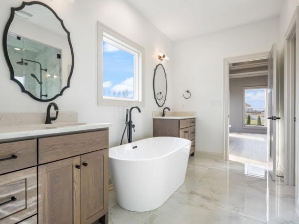 Bright modern bathroom featuring a freestanding bathtub, double vanity, and large window.