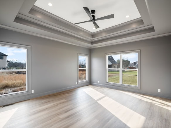 Bright and spacious living room with large windows, light wood flooring, and a ceiling fan.