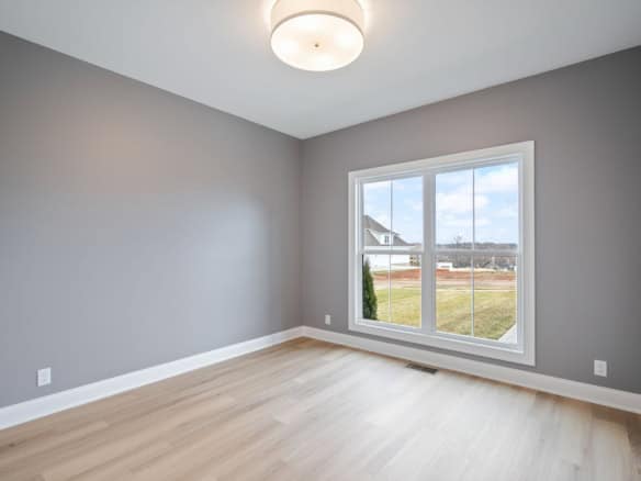 Bright empty room with large window and modern lighting.