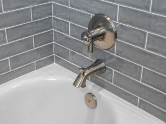 Bathroom faucet with gray tile backsplash in a modern bathroom.