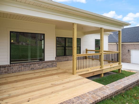 Front porch with wooden deck and railing at a new residential home.
