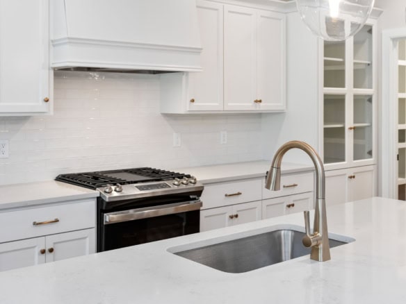 Bright white kitchen with island, stainless steel sink, and cabinetry.