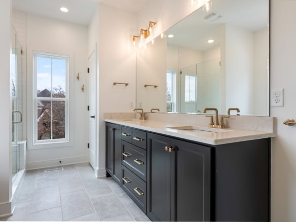 Bright bathroom featuring a double vanity, large window, and modern fixtures.