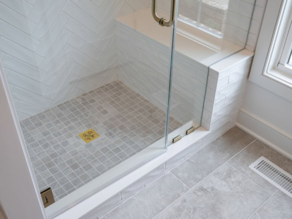 Shower area with glass door, tiled walls, and floor in a contemporary bathroom.
