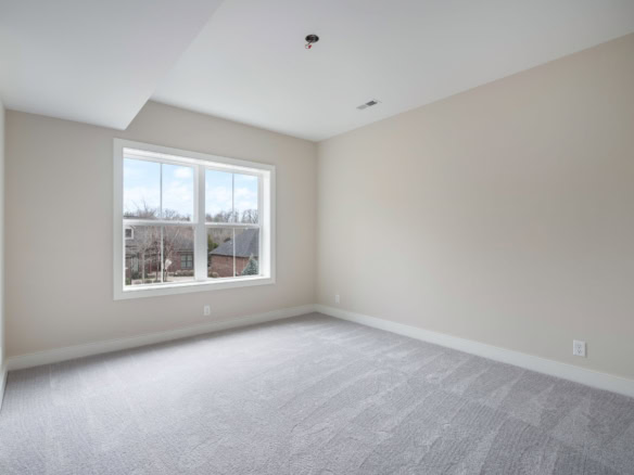 Bright empty room with large window and neutral walls.