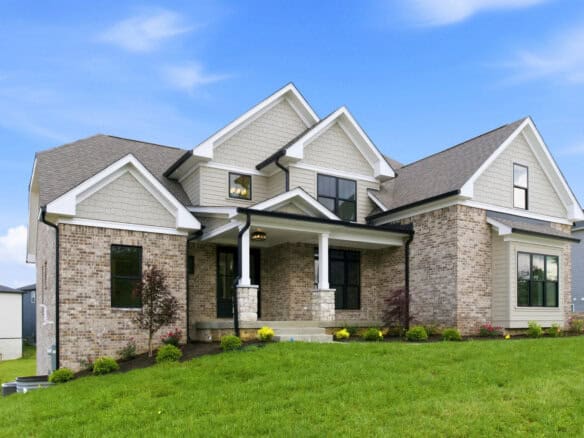Luxury modern home with brick and siding exterior on a green lawn under blue sky.