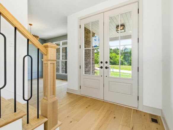 Bright entryway with glass double doors and hardwood flooring.