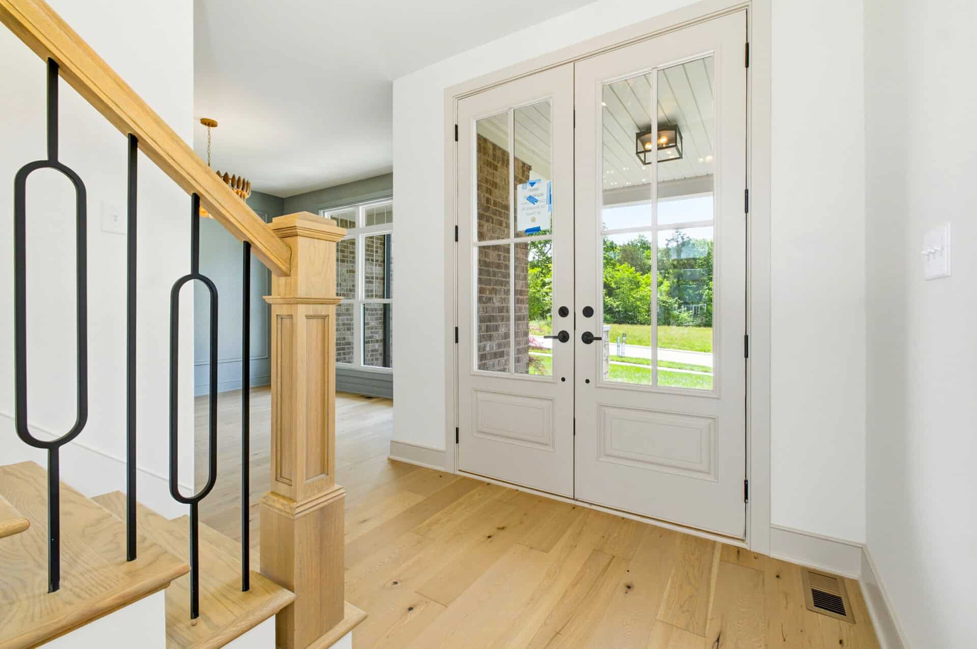 Bright entryway with glass double doors and hardwood flooring.