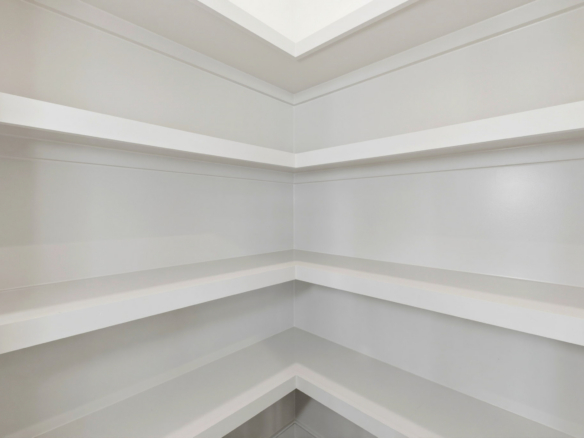 White built-in corner shelving unit with multiple horizontal shelves wrapping around the corner.