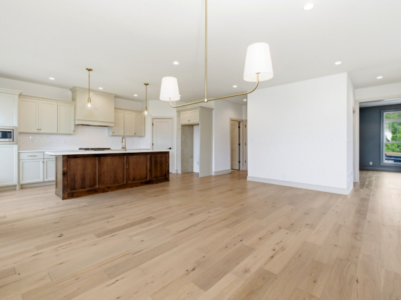 Bright open kitchen with white cabinets, a dark wood island, and brass pendant lights