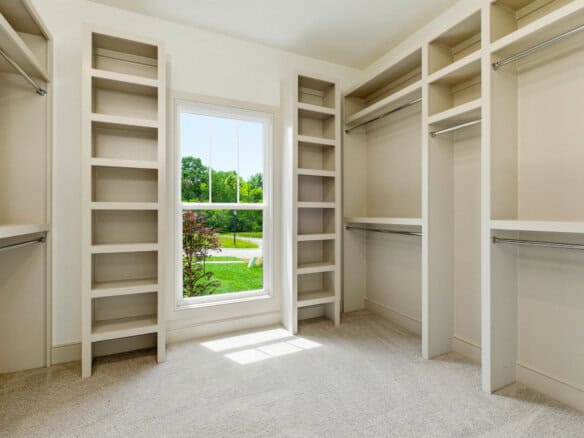 Spacious walk-in closet with built-in shelves and a window overlooking greenery.