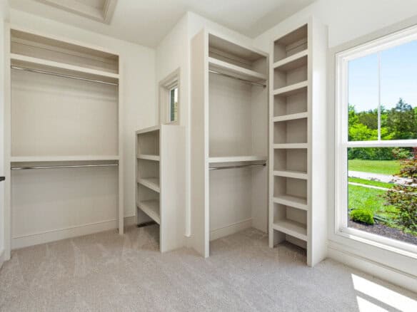 Spacious walk-in closet with built-in shelves and a large window showing greenery.