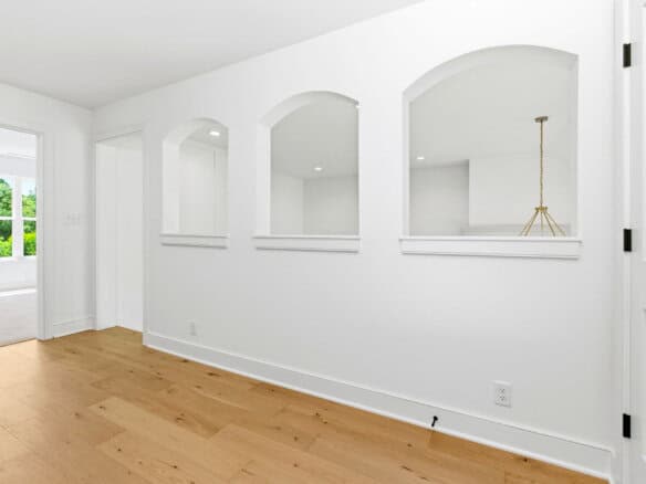 Bright interior with white walls, arched openings, and light wood flooring.