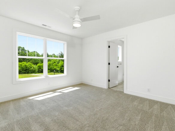 Bright empty room with large window and white walls in a new home.