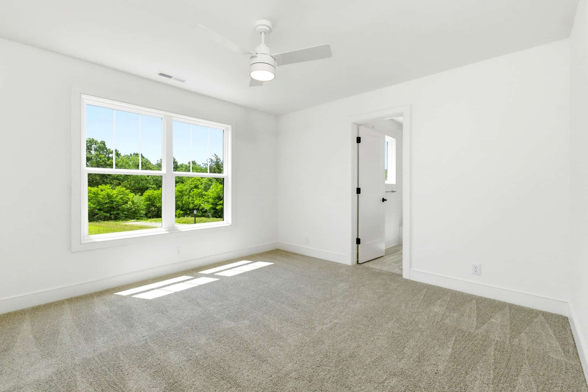 Bright empty room with large window and white walls in a new home.