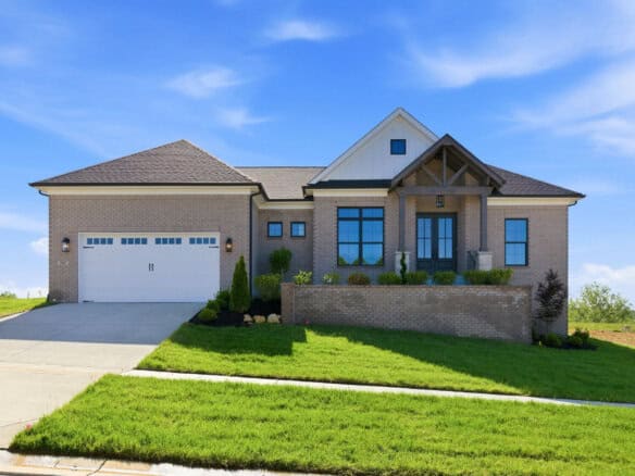 Modern brick home with front porch and well-maintained lawn under blue sky.