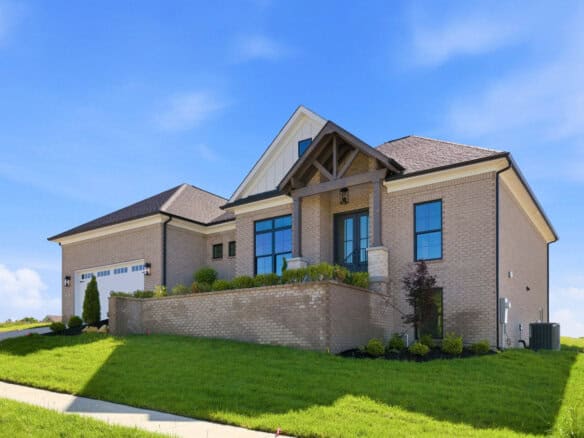 Modern brick two-story house with a gabled roof, front entry, and manicured lawn under a blue sky.