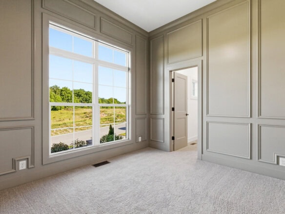 Bright room with large window and neutral wall paneling in a luxury home.
