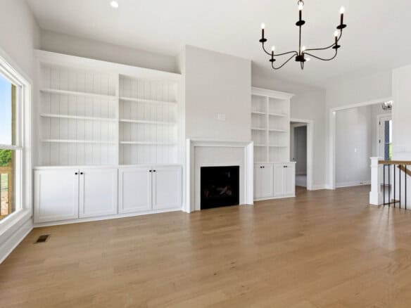 Spacious living room with white built-in shelves and a fireplace.
