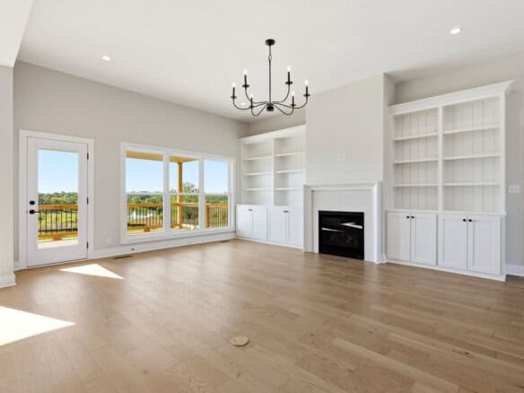 Spacious living room with large windows, white built-in shelves, and a fireplace.