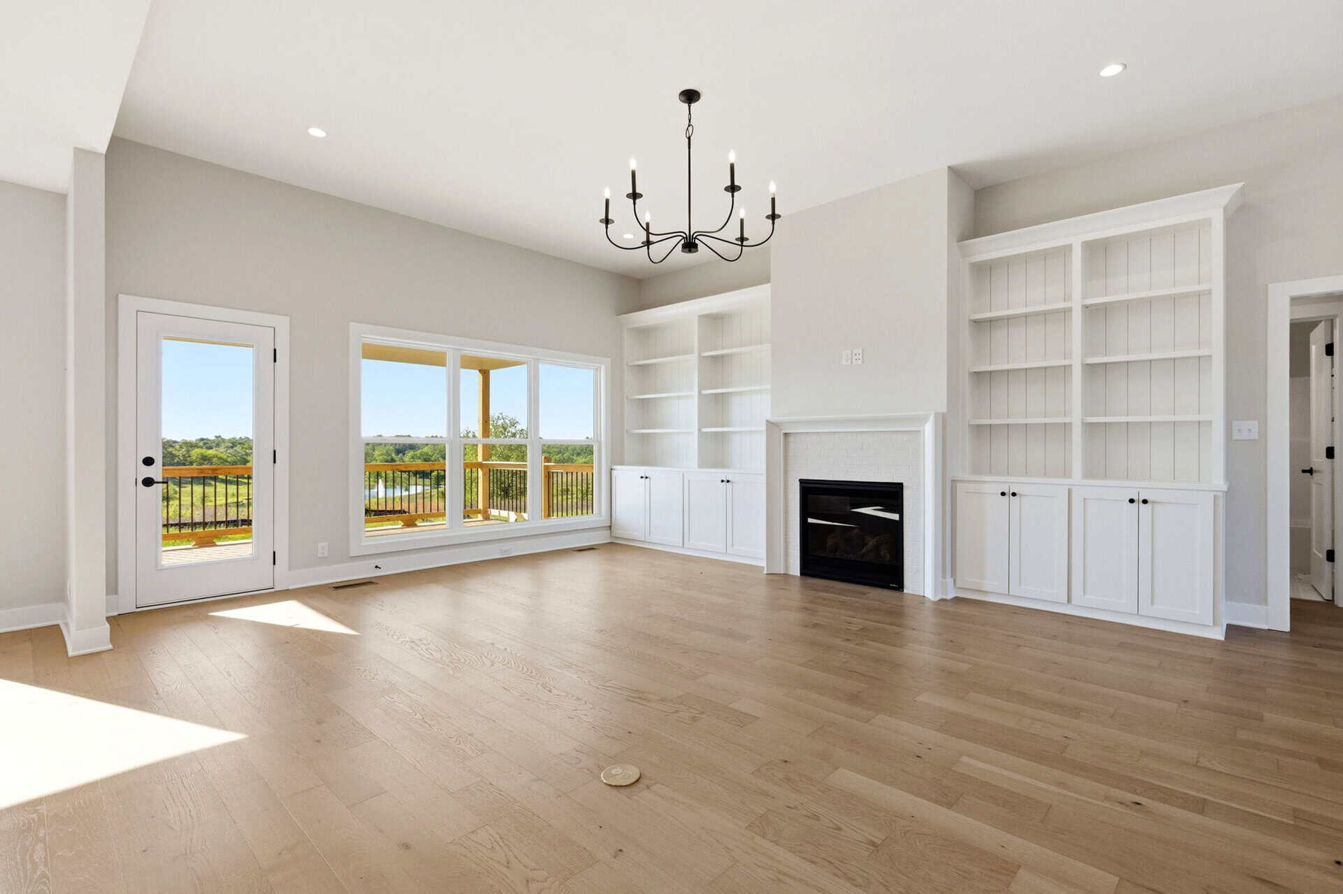 Spacious living room with large windows, white built-in shelves, and a fireplace.