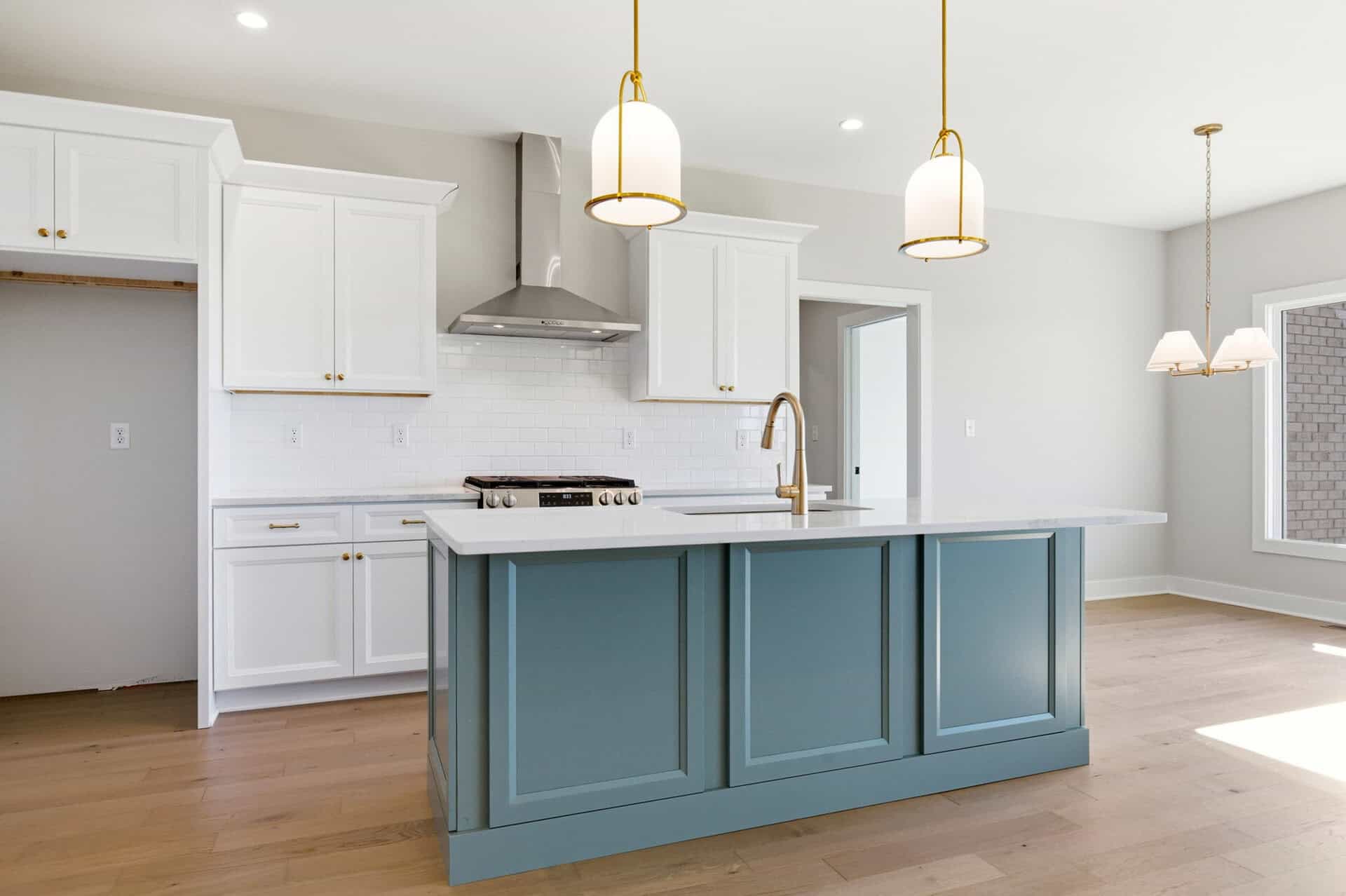 Modern kitchen with white cabinets and blue island in a bright home.