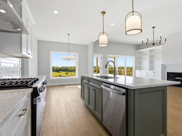 Modern kitchen with island, pendant lights, and large windows overlooking outdoors.