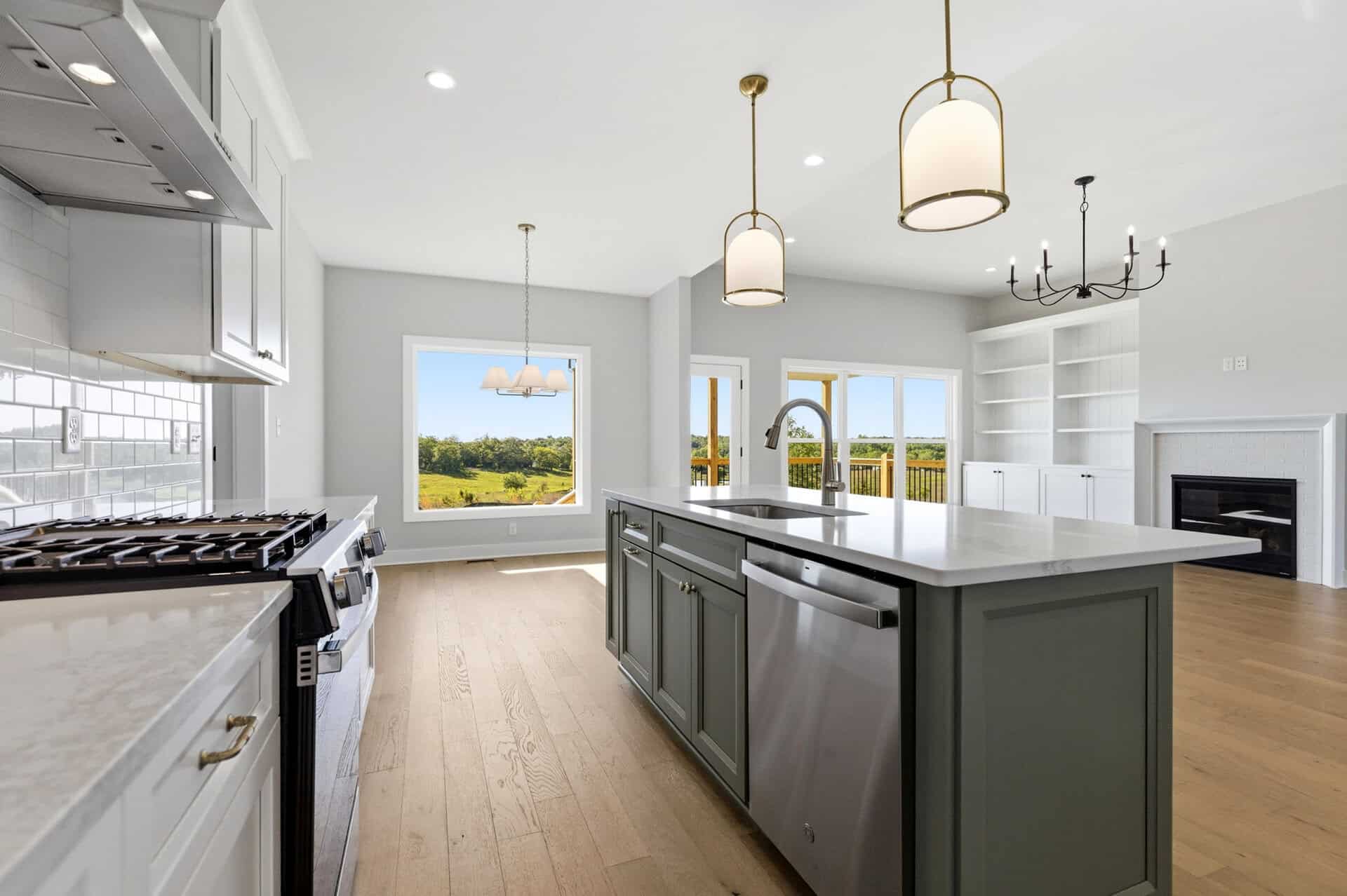 Modern kitchen with island, pendant lights, and large windows overlooking outdoors.