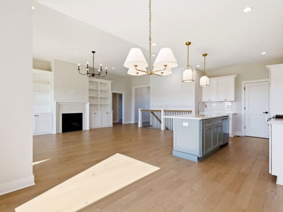 Spacious open-concept kitchen and living area with white cabinetry and hardwood floors.