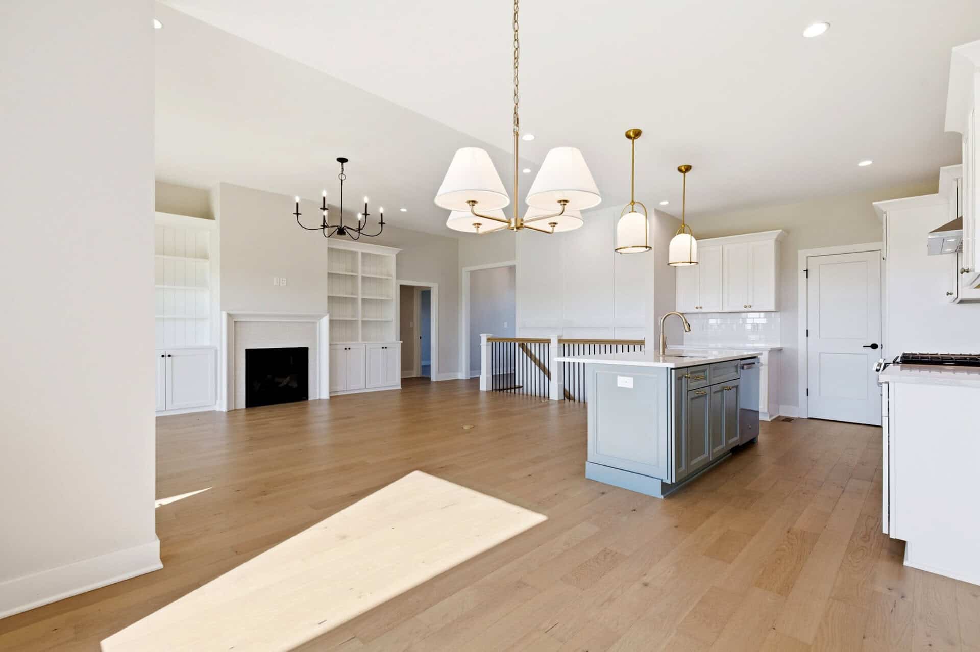Spacious open-concept kitchen and living area with white cabinetry and hardwood floors.