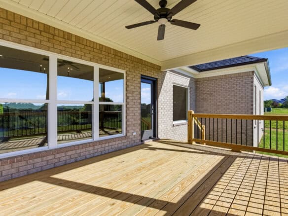 Spacious outdoor deck with railing and view of green landscape and blue sky.