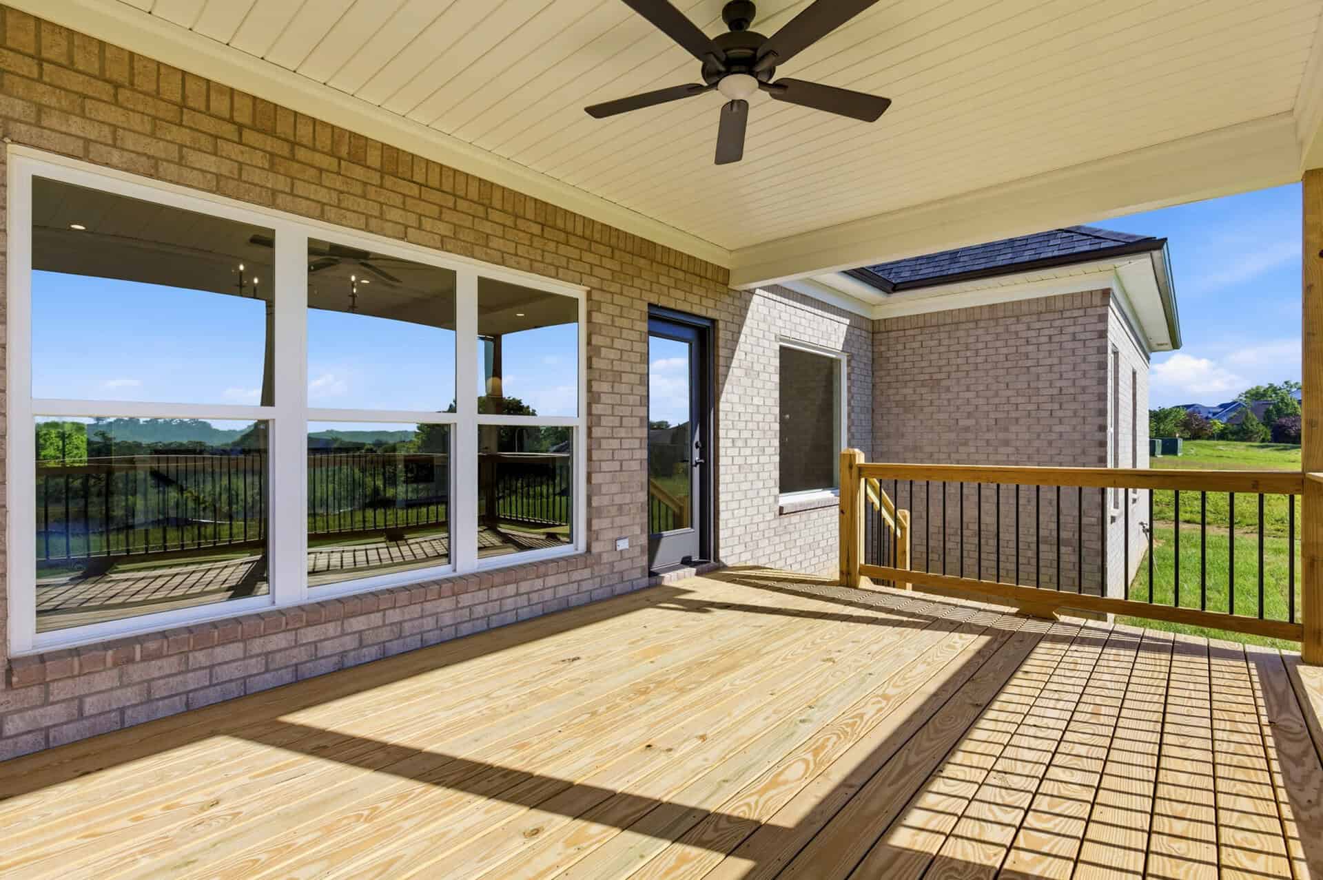 Spacious outdoor deck with railing and view of green landscape and blue sky.