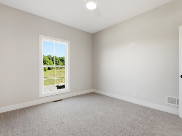 Empty room with a window overlooking green landscape and a white door.