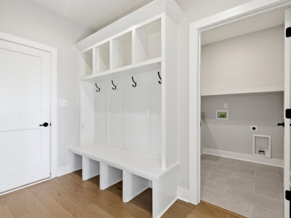 Modern mudroom with built-in hooks and storage bench in white.