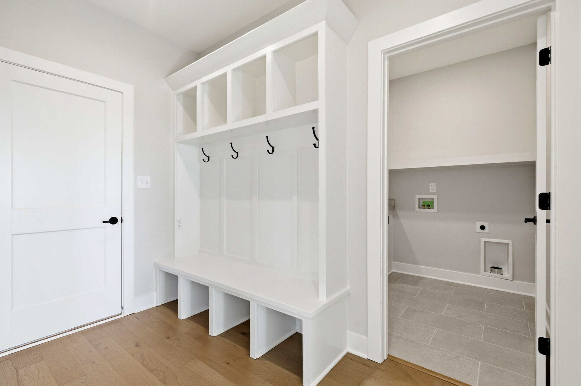 Modern mudroom with built-in hooks and storage bench in white.