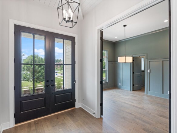 Elegant entryway with black door and view into living room with green walls.