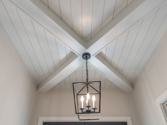 Interior ceiling with white wood paneling and a black chandelier.