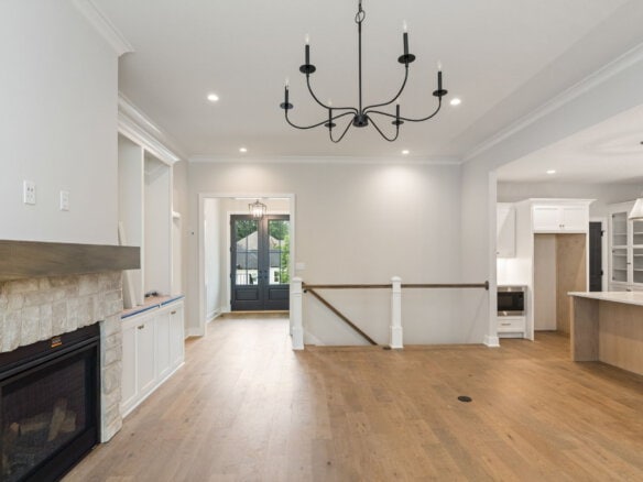 Spacious living room with fireplace, chandelier, and open kitchen area in a modern home.