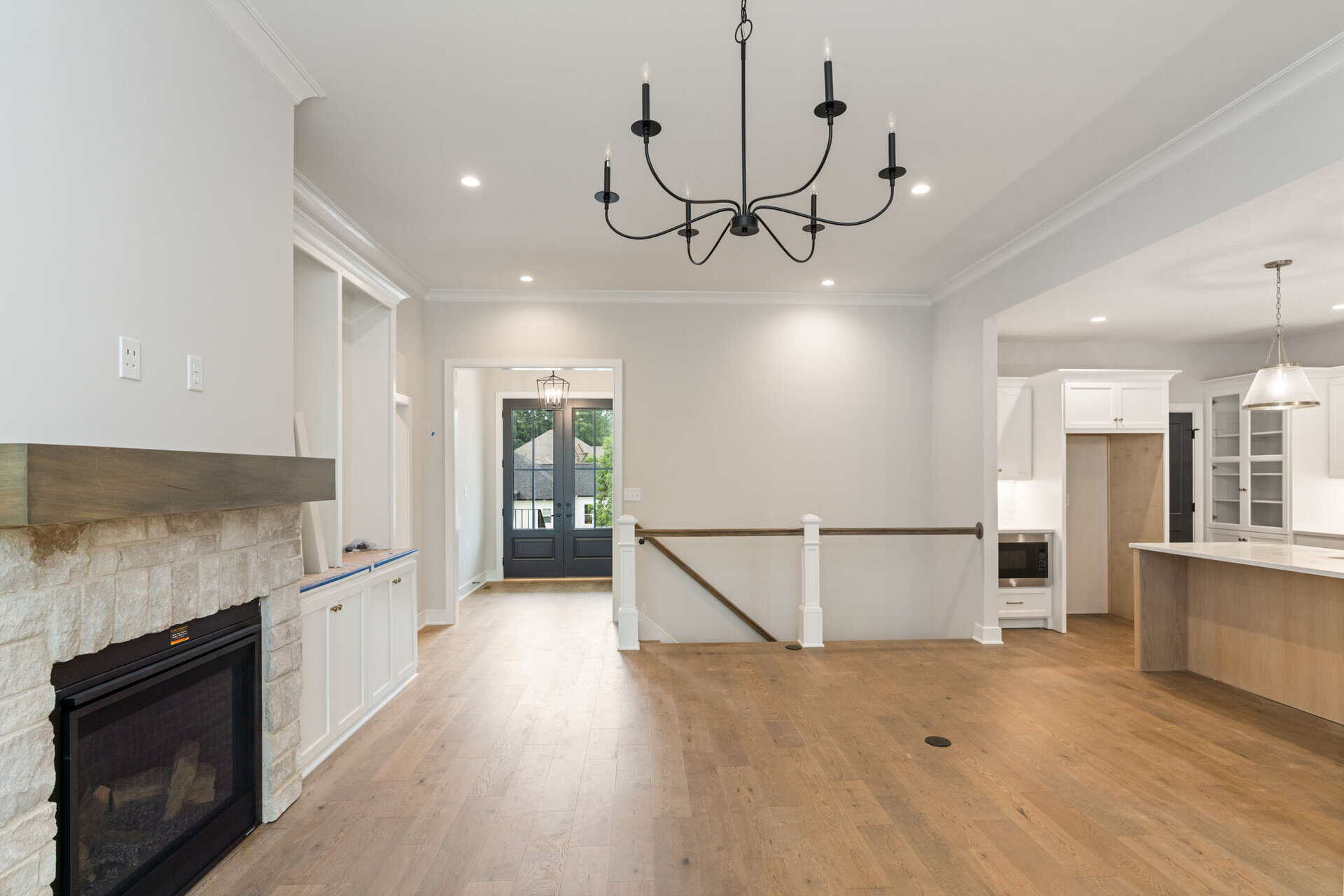 Spacious living room with fireplace, chandelier, and open kitchen area in a modern home.