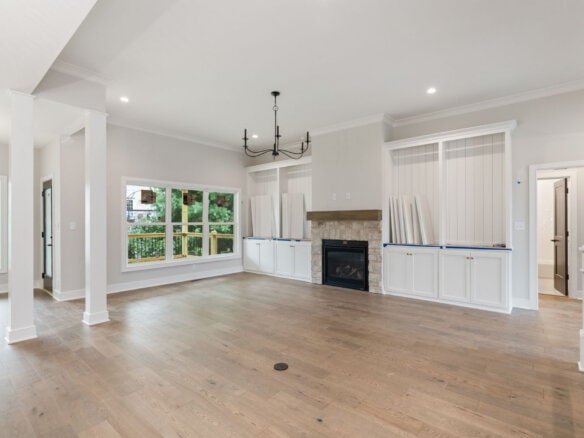 Spacious living room with large windows, fireplace, and hardwood floors.