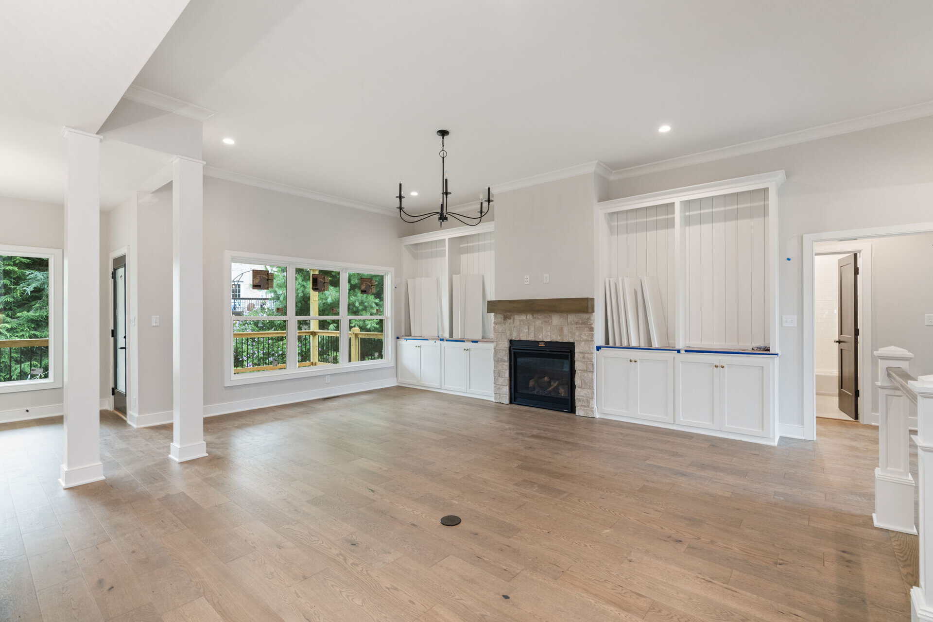 Spacious living room with large windows, fireplace, and hardwood floors.