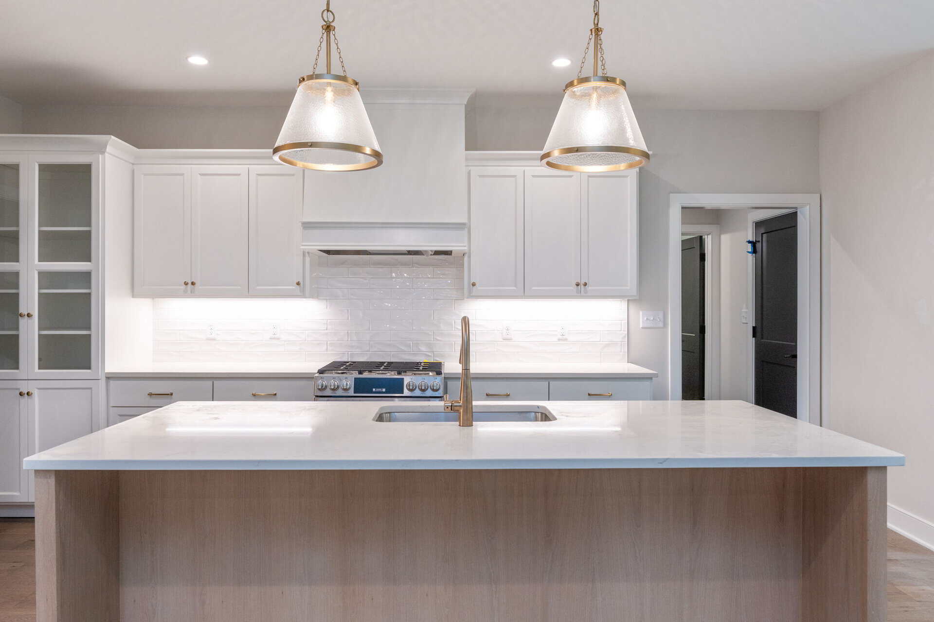 Modern kitchen with white cabinets, island, and pendant lighting.