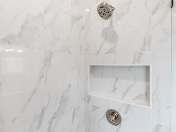 Close-up of a modern shower with marble tiles and built-in niche.