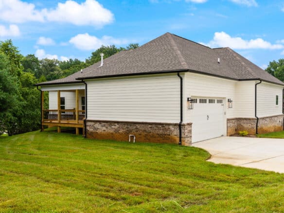 Exterior view of a modern house with a garage and a small porch in a green yard.