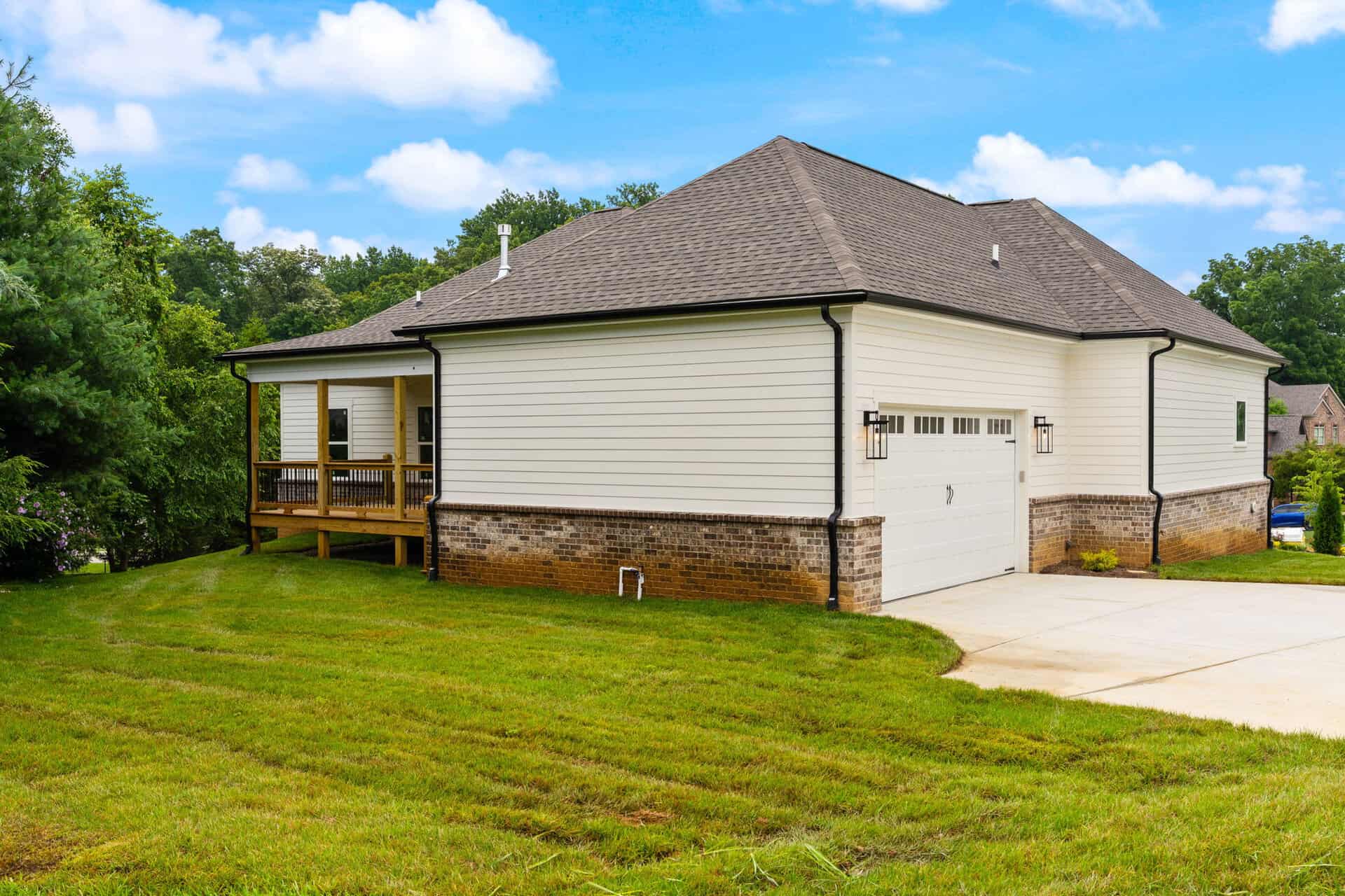 Exterior view of a modern house with a garage and a small porch in a green yard.