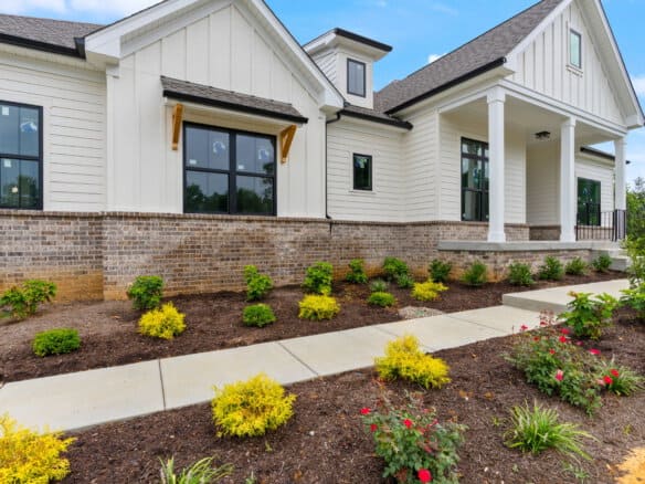 Modern white house with brick foundation and landscaped front yard.
