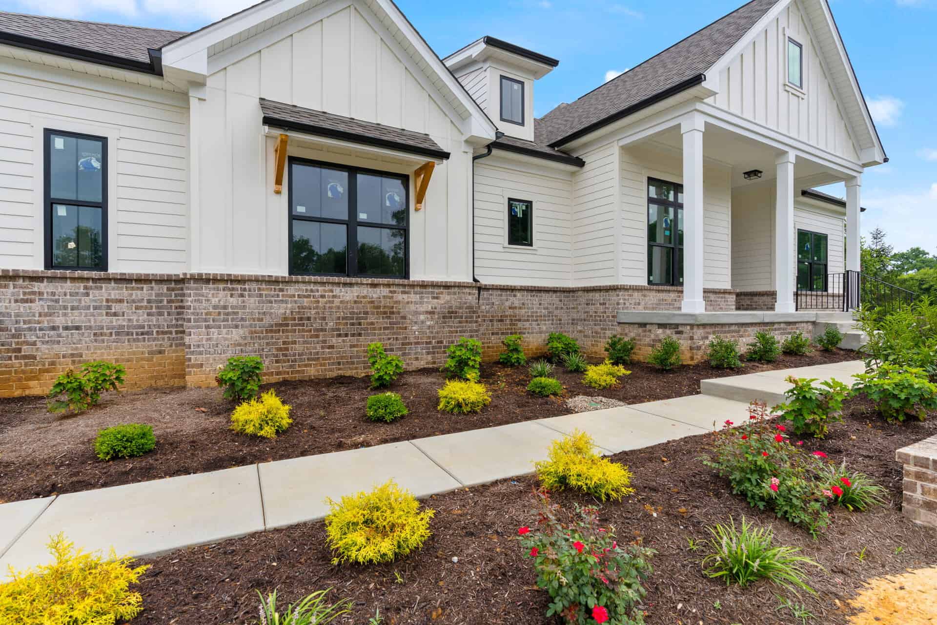 Modern white house with brick foundation and landscaped front yard.