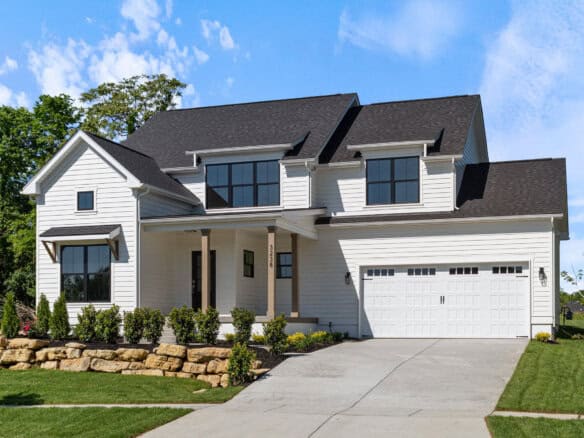 Modern white two-story house with black roof and large garage door.